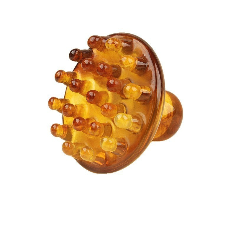 Amber-colored scalp massager on a white background